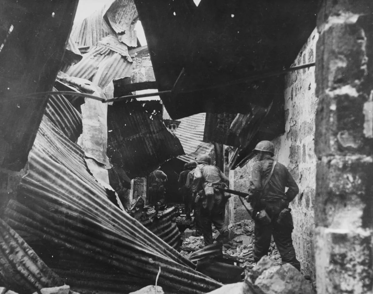 US infantrymen search house to house for Japanese in the ruins of the walled city of Manila, 23 February 1945.