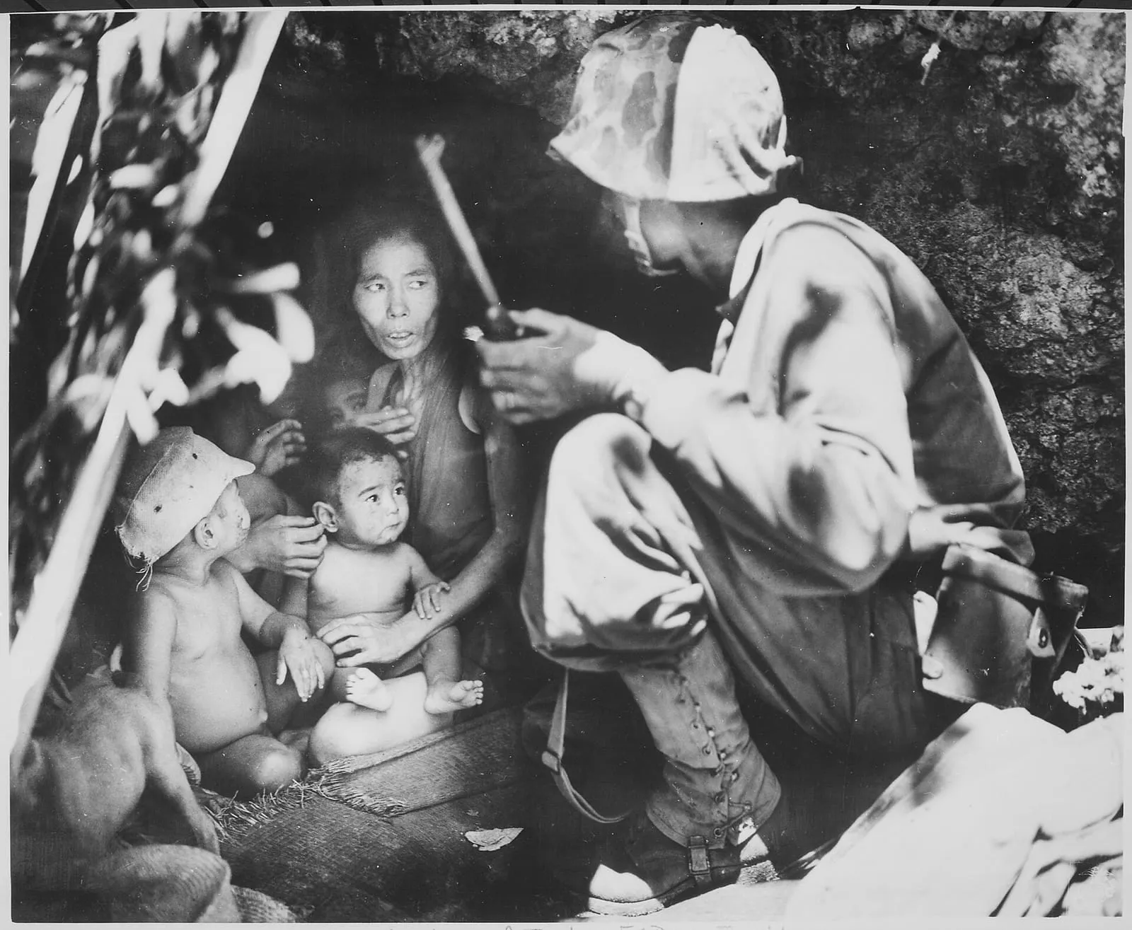 First Lieutenant Robert B. Sheeks of the 2nd Marine Division persuades a woman and her children to leave a cave on Saipan, 21 June 1944.