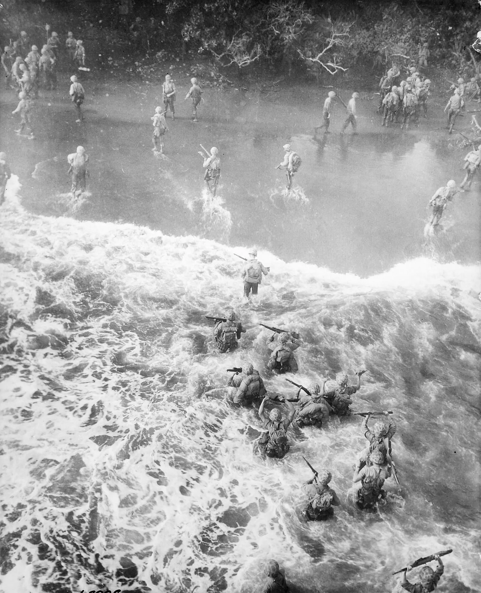 Marines wade through rough water as they leave their LST to take the beach at Cape Gloucester, New Britain, 26 December 1943.