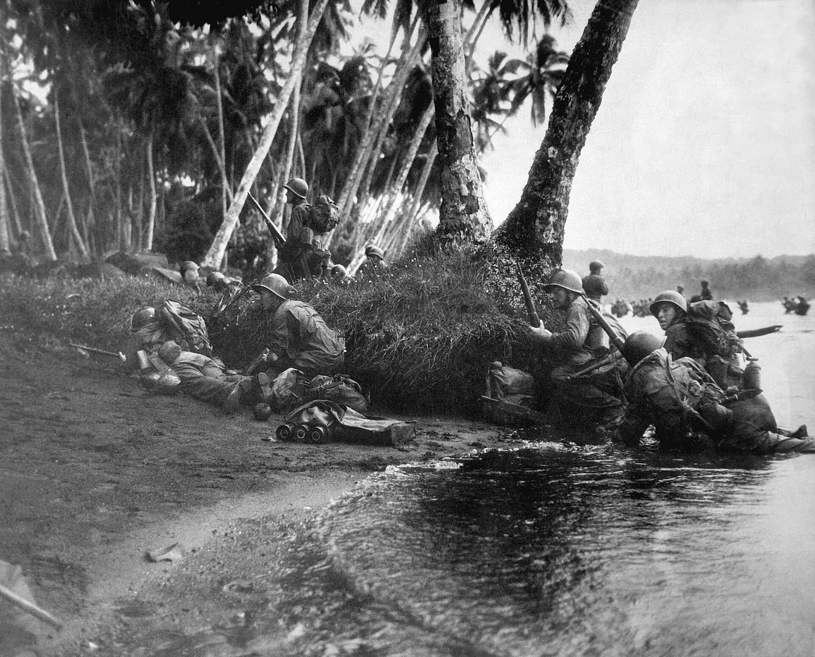 The first Americans ashore on Rendova Island take cover behind tree trunks during the landing, 30 June 1943.