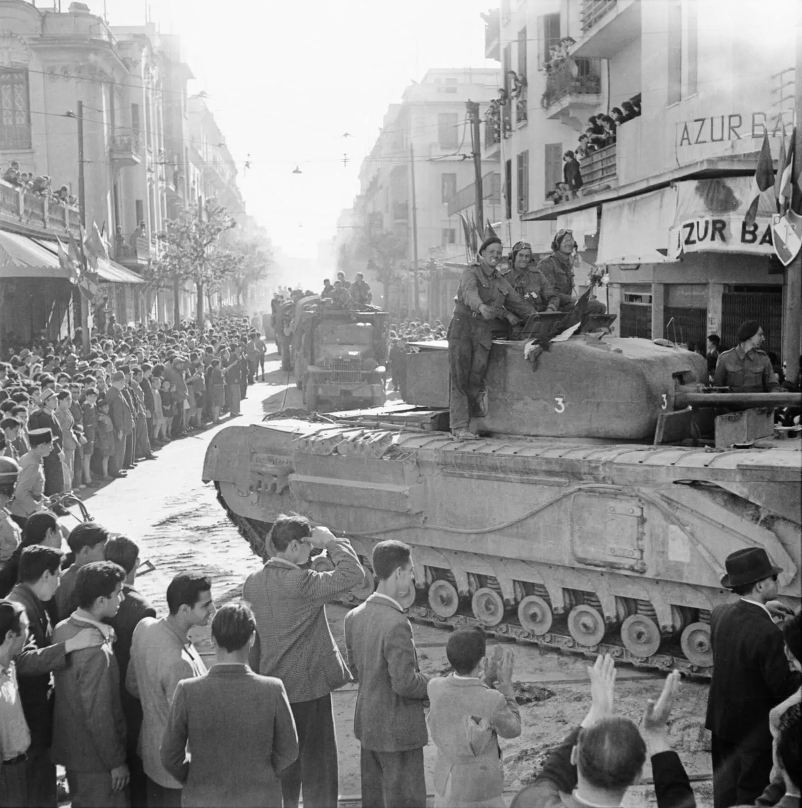 A Churchill tank and other vehicles parade through Tunis, 8 May 1943.