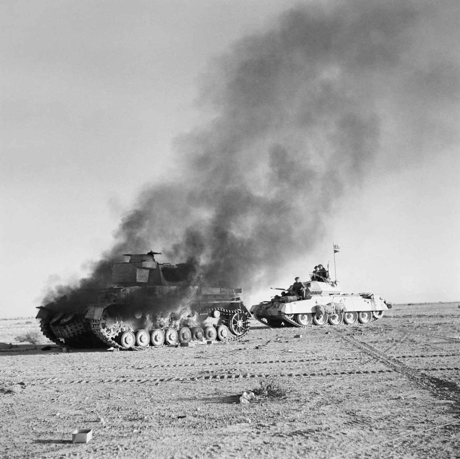 A British Crusader tank passes a burning German Panzer IV during Operation Crusader, 27 November 1941.